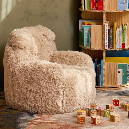 Cream Beari Kids Armchair in a reading nook beside a bookshelf and wooden toy blocks 