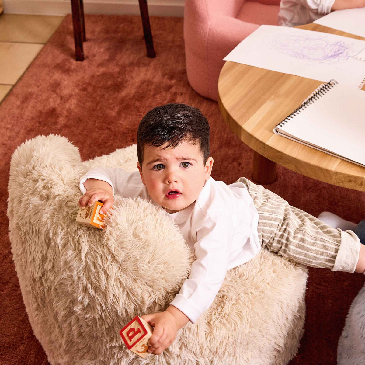 Toddler holding wooden blocks in the cream Beari Kids Armchair 