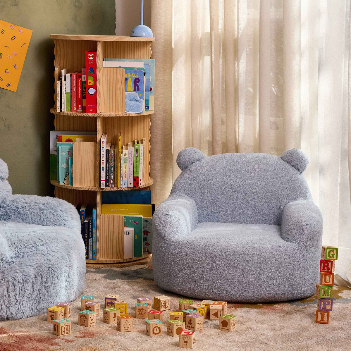 Blue Teddi Kids Armchair in a reading nook beside a bookshelf and wooden toy blocks 