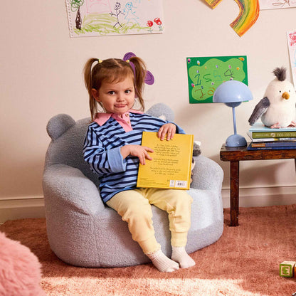 Girl holding a picture book in the blue Teddi Kids Armchair 