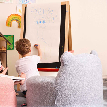 Boy drawing at an easel behind the blue Teddi Kids Armchair 