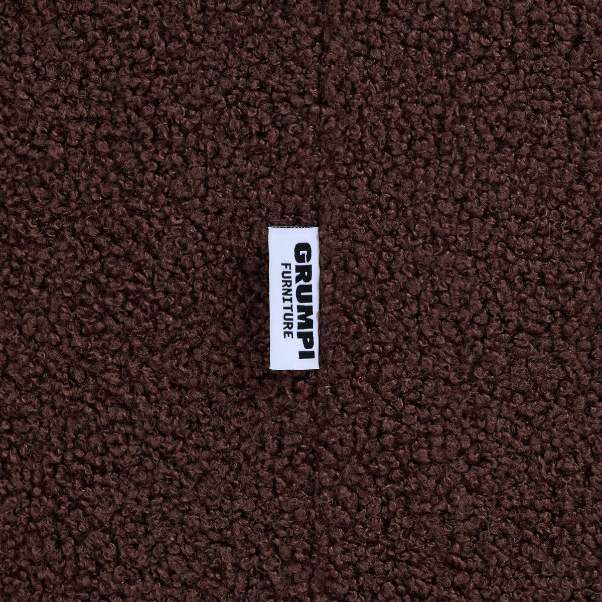 Close-up of the brown teddy fabric on the Teddi Kids Armchair, with the Grumpi Furniture label 