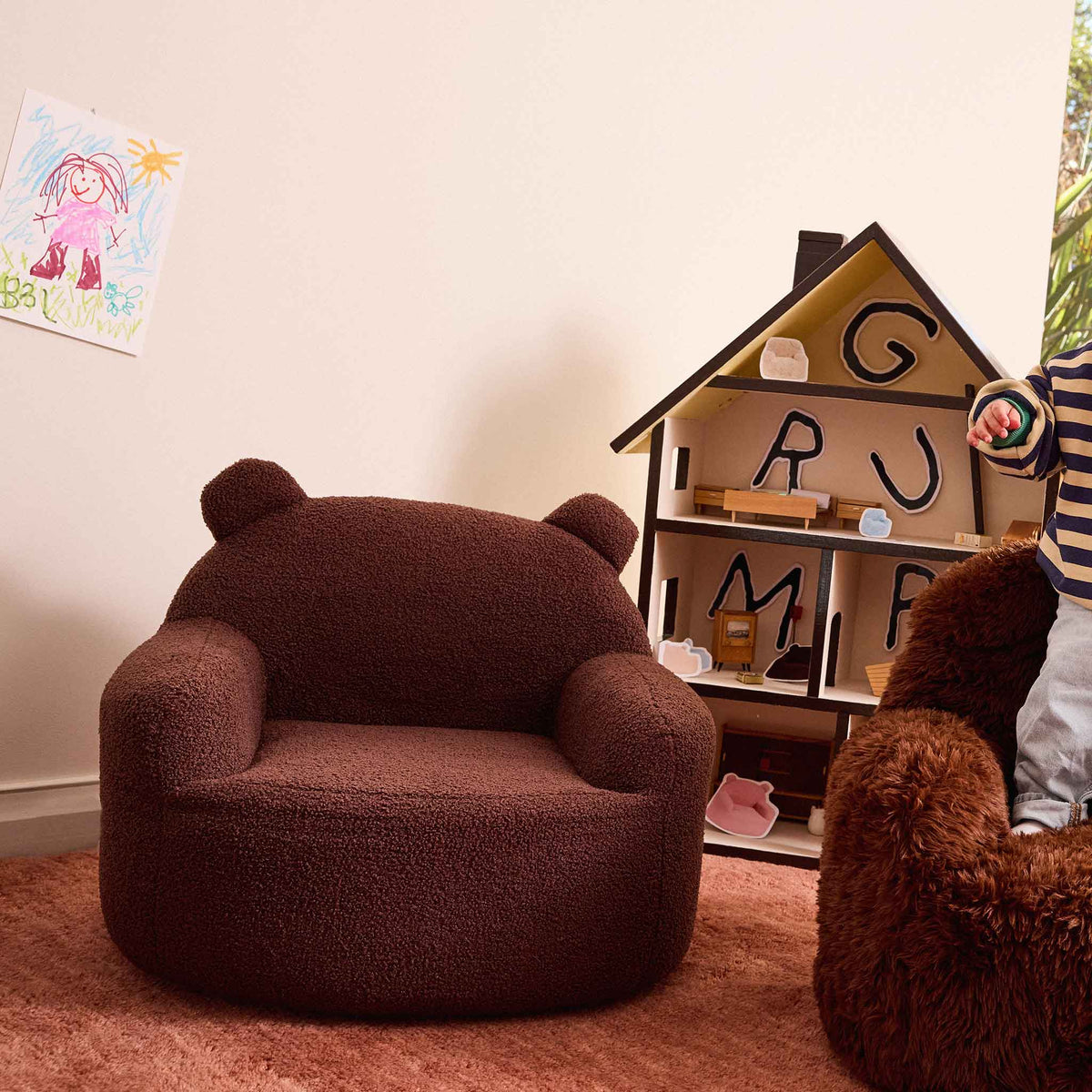 Brown Teddi Kids Armchair beside a wooden dollhouse on a pink rug 