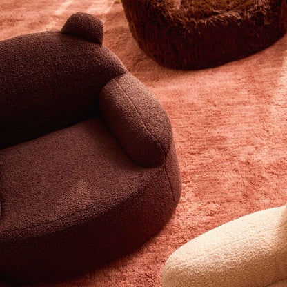 Overhead view of the brown Teddi Kids Armchair on a pink rug 