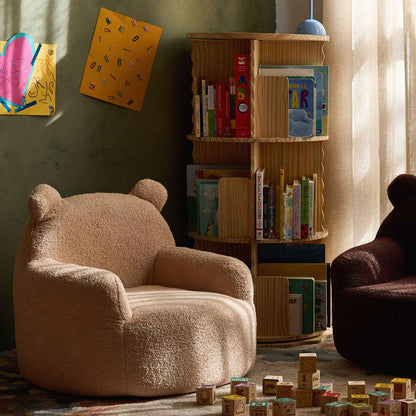 Cream Teddi Kids Armchair in a reading nook beside a bookshelf and wooden toy blocks 