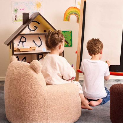 Two children drawing at an easel beside the cream Teddi Kids Armchair and a dollhouse 