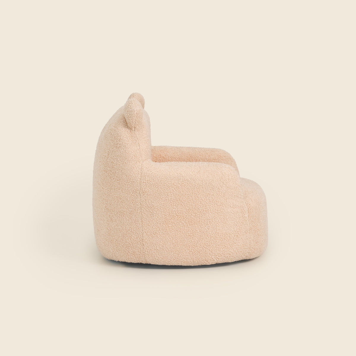 Side view of the cream Teddi Kids Armchair on a beige background 