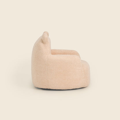 Side view of the cream Teddi Kids Armchair on a beige background 