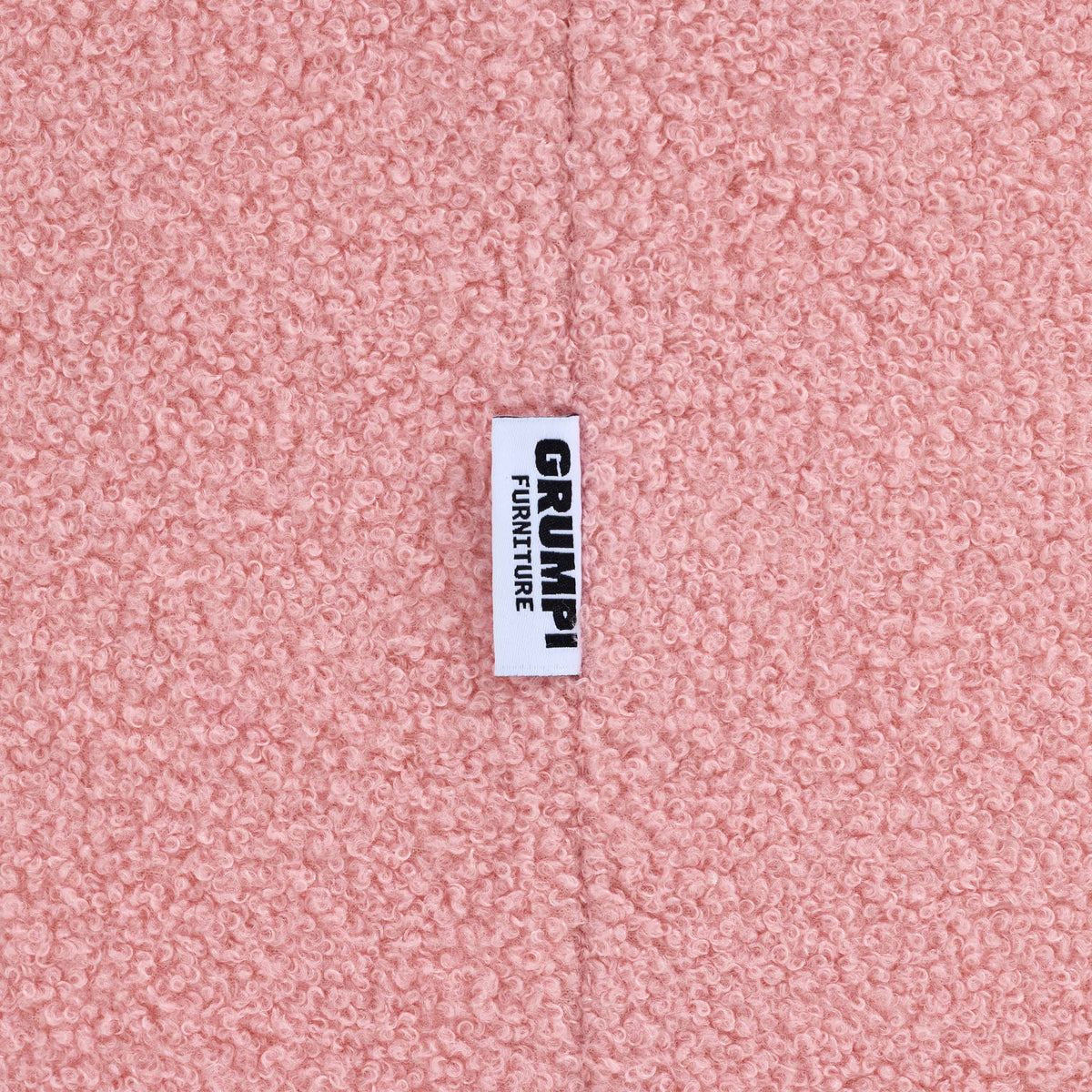 Close-up of the pink teddy fabric on the Teddi Kids Armchair, with the Grumpi Furniture label 