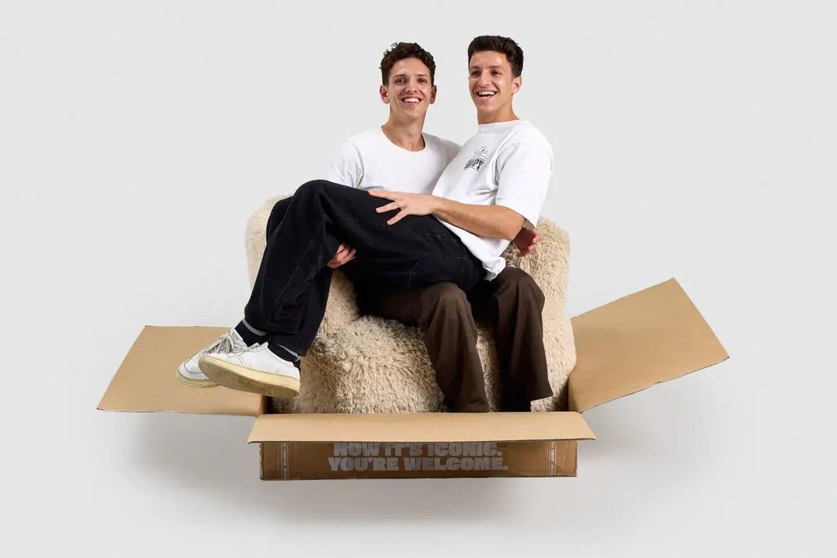Cory and Dion, the brothers behind Grumpi, sitting in a Grumpi chair in its box